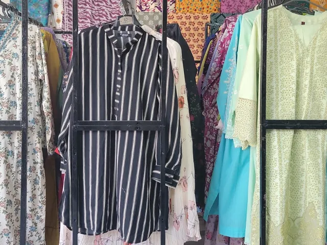 Stitched shirts on the rails inside the shop, a striped black shirt in front