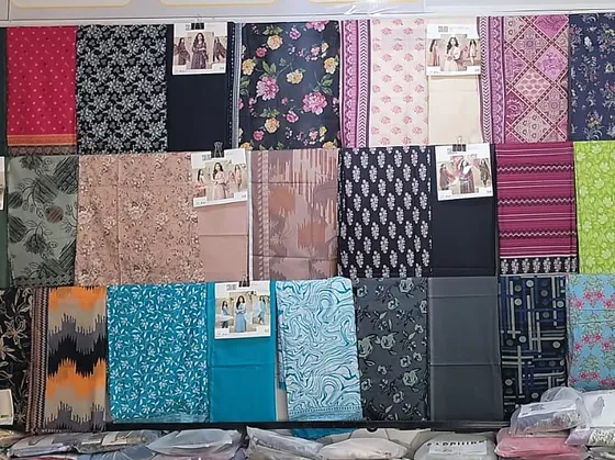 Unstitched suit fabric on the shelves, each pack with its catalogue picture clipped on